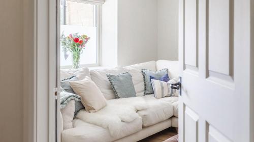 a white couch in a living room with a vase of flowers at A handsome large 9 bedroom 17th Century village house moments from The Cotswold Way offering modern luxury in a peaceful location in Frocester