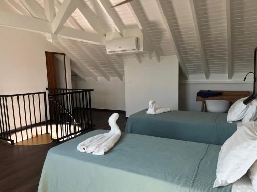 Una habitación con dos camas con un cisne. en Colombus Résidence en Oyster Pond
