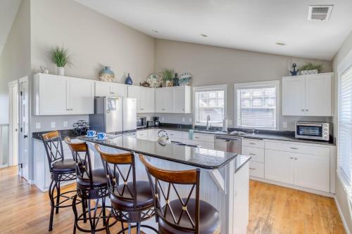 a kitchen with white cabinets and a island with bar stools at The Spindrift House in Lincoln City