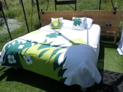 a bed with a green and white comforter with pillows at Nuits D'y Cîmes : Nuit Insolite Bulle, SPA in Jaunac