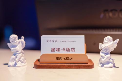 two white figurines of people standing next to a box at Xinghe Yuezhi S Hotel to Guangzhou Yuexiu Park Railway Station Subway Station Baima Clothing City Flagship Store in Guangzhou
