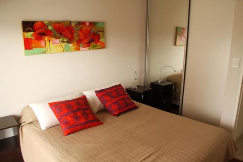 a bedroom with a bed with two red pillows on it at Cordoba Rent Centro Avellaneda in Córdoba