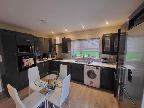 cocina con mesa y lavadora en Kilronan Holiday Homes en Kilronan