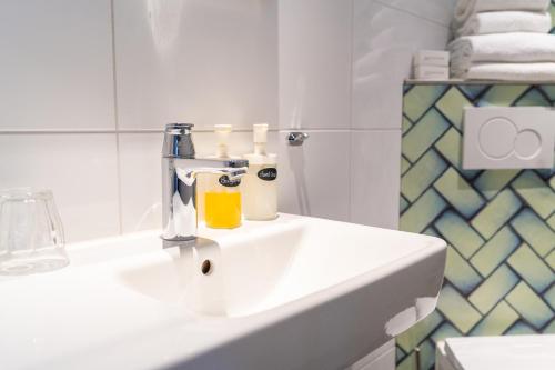 a bathroom with a white sink with bottles on it at Kruller - Hotel B&B in Otterlo