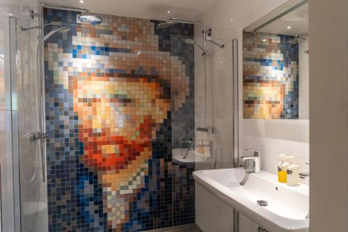 ein Badezimmer mit einem Mosaik eines Mannes in der Dusche in der Unterkunft Ontbijthotel Kruller in Otterlo