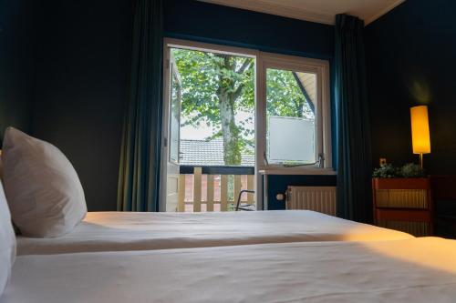 een slaapkamer met een groot bed en een raam bij Ontbijthotel Kruller in Otterlo