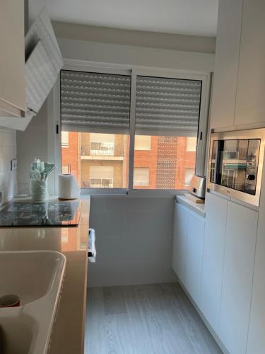 een keuken met een wastafel en een raam met jaloezieën bij Apartamento nuevo en Puertollano in Puertollano
