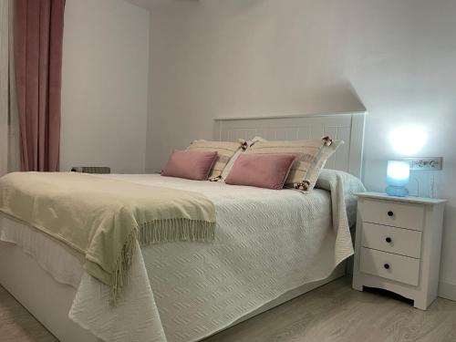 een slaapkamer met een bed met roze kussens en een nachtkastje bij Apartamento nuevo en Puertollano in Puertollano