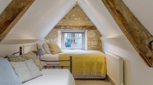 a attic bedroom with two beds and a window at A handsome large 9 bedroom 17th Century village house moments from The Cotswold Way offering modern luxury in a peaceful location in Frocester