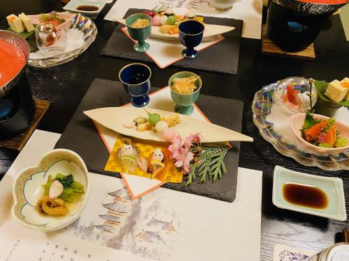 une table avec plusieurs assiettes de nourriture dans l'établissement Ryokan TANAKAYA, à Minobu