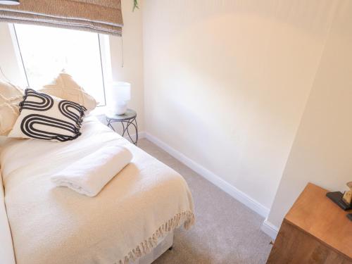 a white room with a bed with a window at Rose Cottage in Brough