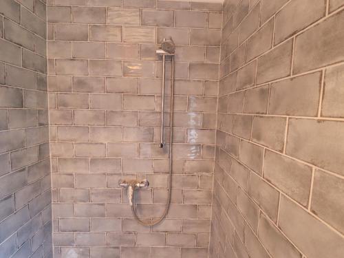 eine Dusche im Bad mit Ziegelwand in der Unterkunft Rose Cottage in Brough