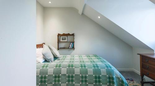 a bedroom with a bed with a green blanket at A handsome large 9 bedroom 17th Century village house moments from The Cotswold Way offering modern luxury in a peaceful location in Frocester