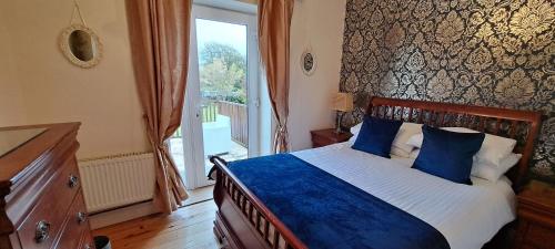 Un dormitorio con una cama con almohadas azules y una ventana en Kilronan Holiday Homes, en Kilronan