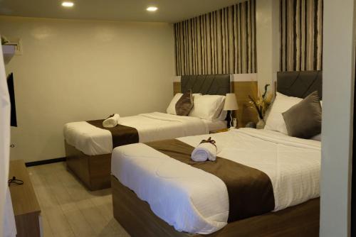duas camas num quarto de hotel com lençóis brancos em VIEDA HOTEL em Caticlan