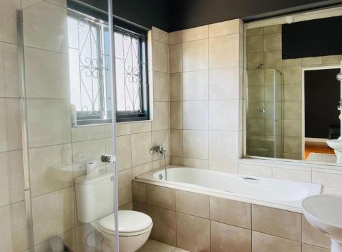 a bathroom with a tub and a toilet and a sink at Alberta Bed and Breakfast in Pietermaritzburg