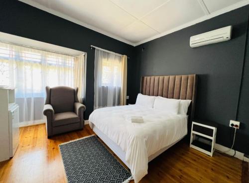 a bedroom with a large bed and a chair at Alberta Bed and Breakfast in Pietermaritzburg