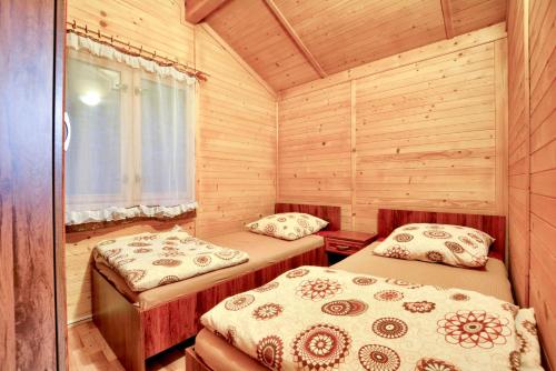 um quarto com 2 camas num chalé de madeira em Ośrodek Wypoczynkowy "Puszczyk" Wolnostojące Domki z Bali em Sieraków
