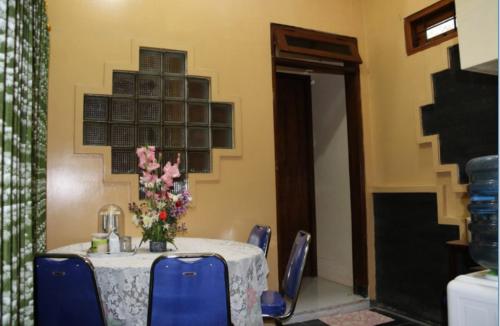 une table avec des chaises bleues et un vase de fleurs. dans l'établissement Joyful Home 2, à Yogyakarta