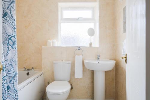 a bathroom with a toilet and a sink and a window at Bibury House a lovely 2 bed house sleeps 4 in Witney