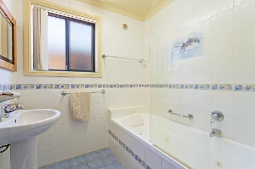 a white bathroom with a sink and a tub and a sink at Snug Cove Villas in Eden