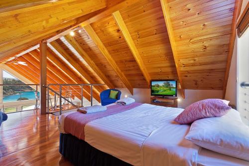 a bedroom with a large bed in a room with wooden ceilings at Snug Cove Villas in Eden