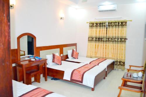 1 Schlafzimmer mit 2 Betten, einem Tisch und einem Spiegel in der Unterkunft Khách sạn Anh Đào in Lạng Sơn
