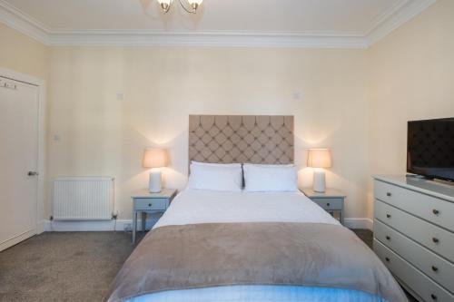 een slaapkamer met een groot bed en 2 nachtkastjes bij Golfers Cottage close to beach, Monifieth and Carnoustie courses in Monifieth
