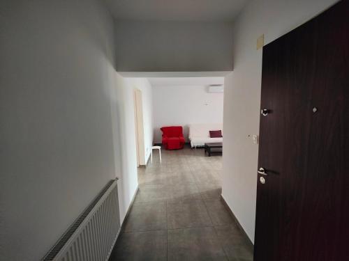 um corredor com um quarto com uma cama e uma cadeira vermelha em Apartament spațios em Bragadiru