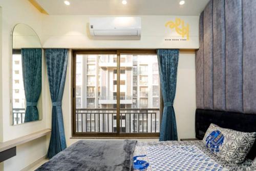Schlafzimmer mit einem Fenster mit blauen Vorhängen und einem Bett in der Unterkunft Swati Chrysantha in Ahmedabad