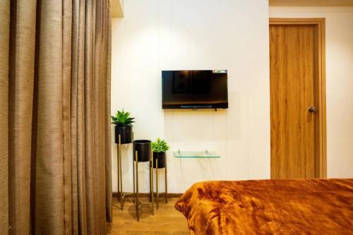 a hotel room with a bed and a flat screen tv at Swati Chrysantha in Ahmedabad