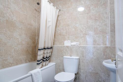 a bathroom with a toilet and a tub and a sink at Luxury one bed Apartment in Carterton