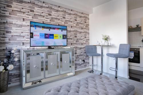 a living room with a flat screen tv on a brick wall at Luxury one bed Apartment in Carterton