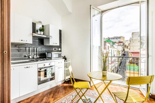 una cucina con armadi bianchi, tavolo e sedie di Bacoli Sveva Luxury House - Terrace & Design a Bacoli