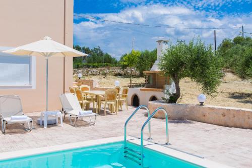 a swimming pool with a table and chairs and an umbrella at Domas Blue Studio Villa With Private Pool and Panoramic View in Loutra