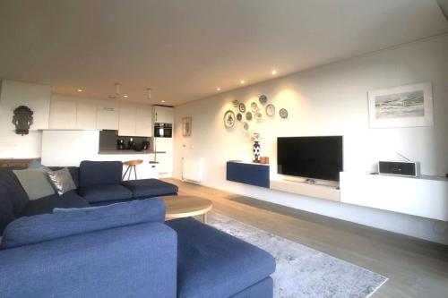 a living room with a blue couch and a flat screen tv at Zeewaarts in Cadzand
