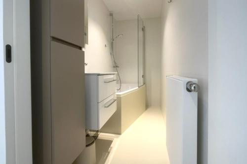 a white kitchen with a sink and a dishwasher at Zeewaarts in Cadzand