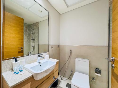a bathroom with a sink and a toilet and a mirror at Comfy Azizi Aura Studio in Dubai
