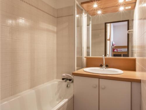 a bathroom with a sink and a tub and a mirror at Appartement La Clusaz, 2 pièces, 5 personnes - FR-1-304-38 in La Clusaz