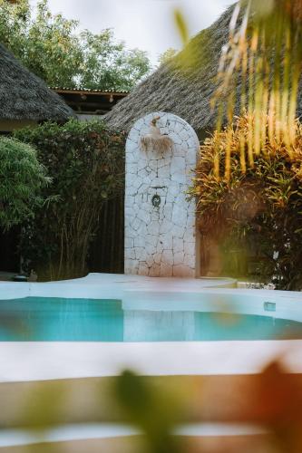 a house with a thatch roof and a swimming pool at Seconda Stella Romantic Hideaway in Jambiani