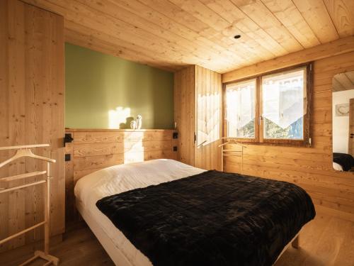 une chambre avec un lit dans une cabane en bois dans l'établissement Chalet 4****, 12 pers, prestations de qualité, terrasse, garage, rénové 2021 - FR-1-304-270, à La Clusaz