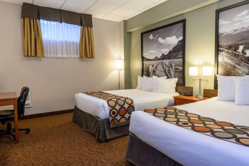 a hotel room with two beds and a desk at Super 8 by Wyndham Cochrane in Cochrane