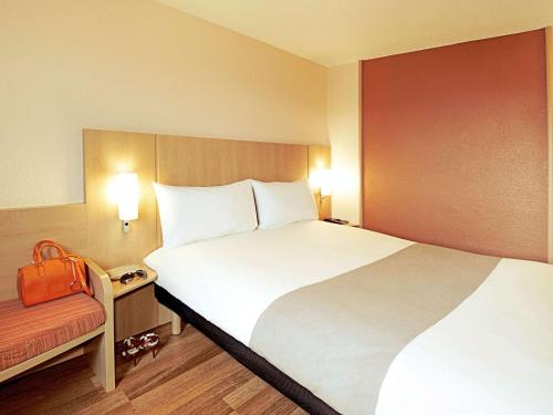 ein Hotelzimmer mit einem großen Bett und einer roten Wand in der Unterkunft ibis Rotherham East – (M18 / M1) in Rotherham