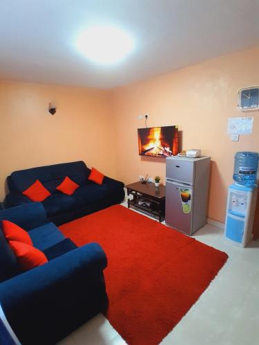 JAYDE COSSY HOMES في ناكورو: غرفة معيشة مع أريكة زرقاء وسجادة حمراء