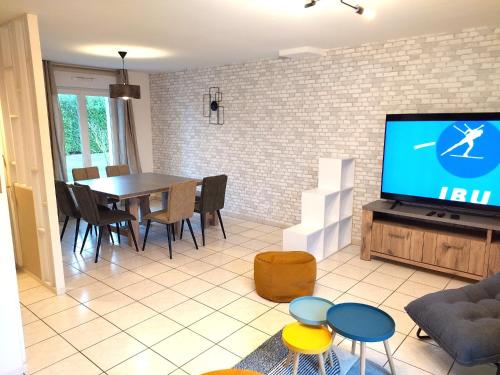 a living room with a television and a table and chairs at Gite de Amiens Poulainville in Poulainville