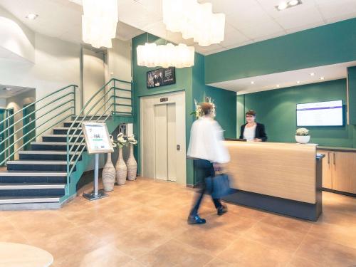 ティオンヴィルにあるHôtel Mercure Thionville Centre Porte du Luxembourgの女の人がサロンのカウンターに立っている