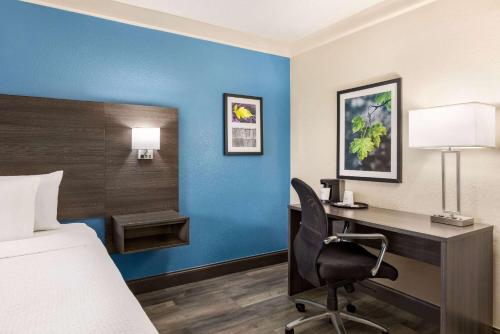 a hotel room with a bed and a desk with a computer at La Quinta Inn by Wyndham San Antonio I-35 N at Toepperwein in San Antonio