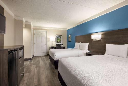 a hotel room with two beds and blue walls at La Quinta Inn by Wyndham San Antonio I-35 N at Toepperwein in San Antonio