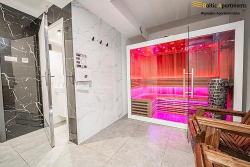 uma casa de banho com um chuveiro com iluminação rosa em Baltic Apartments - Wisus em Świnoujście