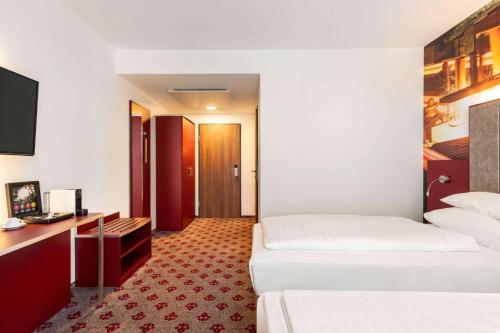 a hotel room with two beds and a desk at Amedia Linz, Trademark Collection by Wyndham in Linz